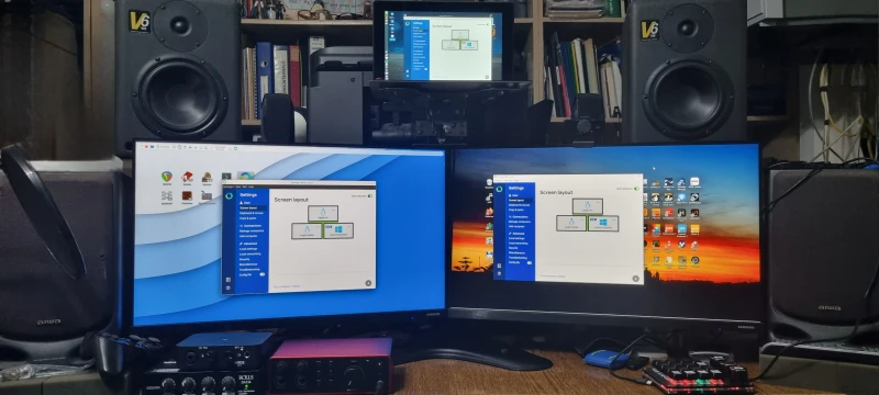 Running Synergy since version 1, this home office and studio setup links three machines across three operating systems. The old Atom box sits center-top so the mouse can slide straight "up" to it from either machine below. A Linux migration is already underway, with Windows 10 on its way out.