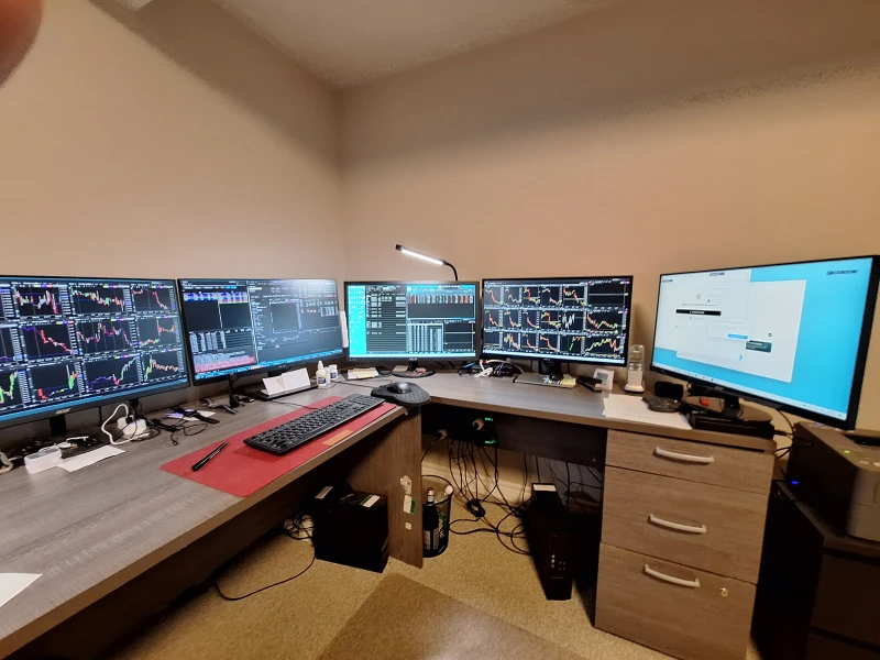 Four machines total: three Dell desktops plus an HP laptop handle what looks like active stock trading across every screen. Synergy lets one keyboard and mouse roam across all of them, keeping the workflow tight when charts need attention fast.