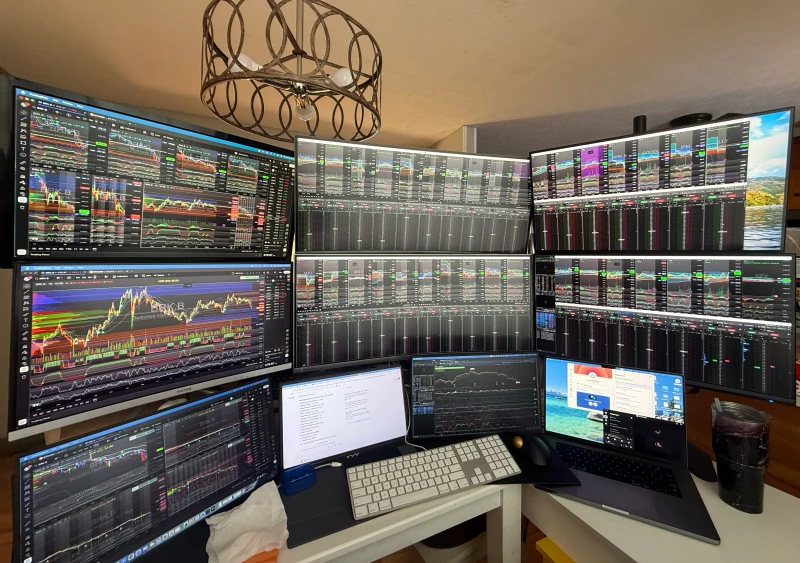 Active stock trading across three machines means charts, scanners, and order flow all need to be visible at once. The Mac Mini handles the left side displays, the custom RTX 3060 PC drives the upper center and right panels, and the MacBook covers additional screens.