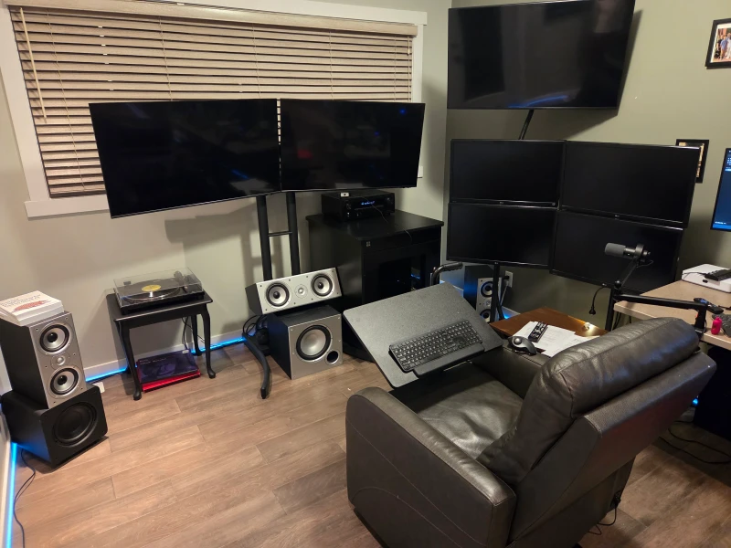 Three HP Z640 workstations feed this room from a mobile server cabinet, spreading across both a recliner-facing wall and a desk. The power recliner with its rotating keyboard tray means the whole thing is operated from a seated position, with a full 5.1 surround system filling in the rest.