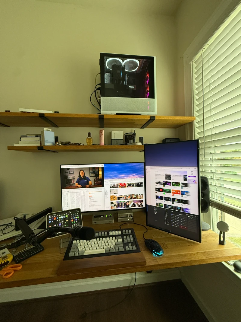 One keyboard and mouse on the main PC controls both machines, with the second PC mounted under the desk and its display running vertically beside the primary monitors.