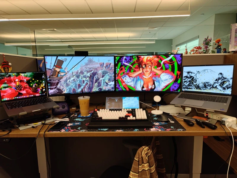 One HP ZBook and one MacBook Pro share this office desk, with Synergy keeping a single keyboard and mouse moving between Windows and macOS without switching inputs. A Wacom tablet sits center desk, pointing to some creative work alongside the day job.