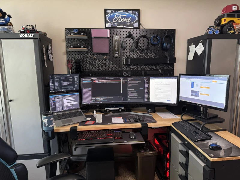 Work on the Dell Precision stays on the Samsung Odyssey while the custom MSI machine, loaded with 128 GB RAM and 1.5 TB of NVMe storage, runs separately on its own 27" display. Synergy keeps one keyboard and mouse shared across both so moving between them is just a cursor slide.